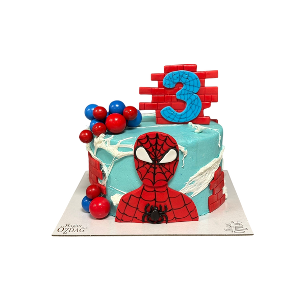 Spiderman-Geburtstagstorte mit blauer Buttercreme, roter Backstein-Optik, handgefertigter Fondant-Spiderman-Figur und dekorativen roten & blauen Kugeln.