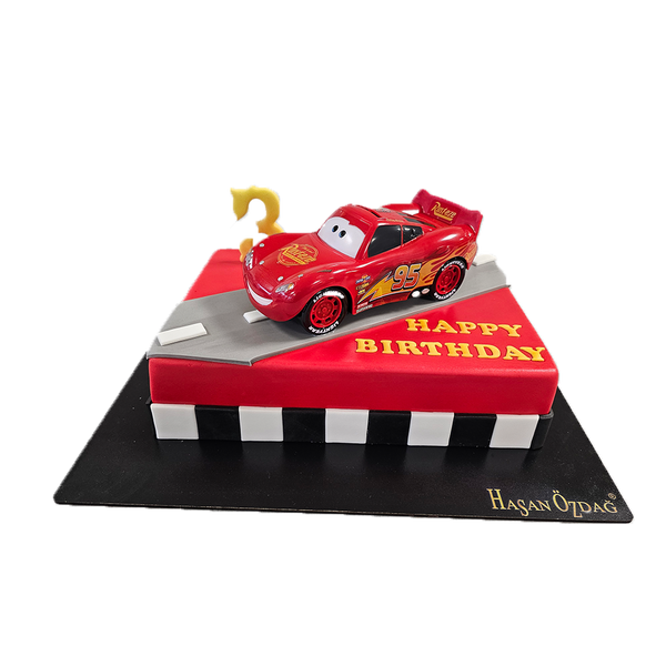 Rote Cars Torte mit  Lightning McQueen Figur. Die Torte ist mit einer Straße und schwarzweißen Rand dekoriert