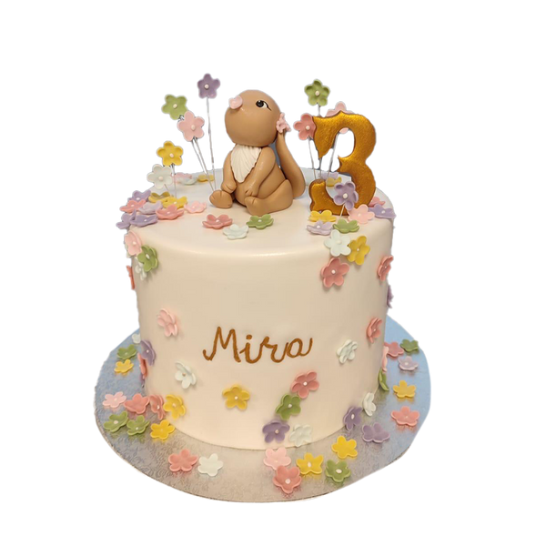 Weiße Torte mit bunten Blumen und Häschen.