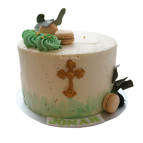 Grün weiße Kofirmationstorte mit goldenen Kreuz, Macarons und Blättern

