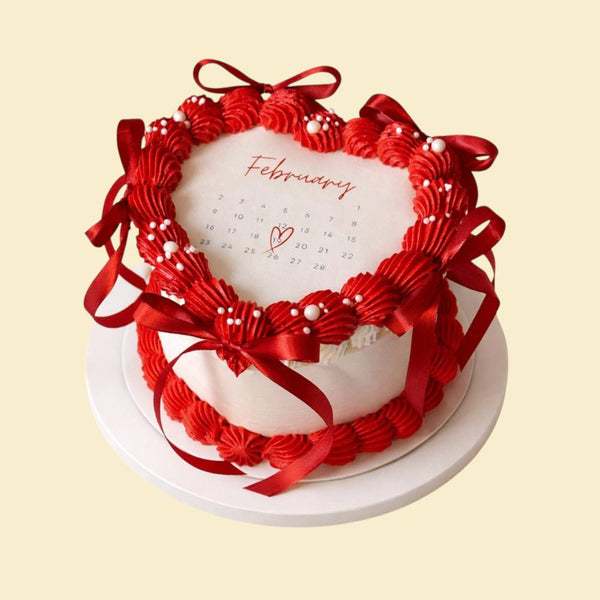 Herzförmige Valentinstagstorte mit rotem Herzrahmen aus Creme, roten Schleifen und Kalenderdesign für Februar, der 14. Februar ist mit einem Herz markiert.