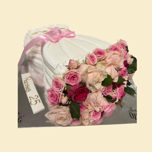 Torten-Blumenstrauß aus weißer Buttercreme in Straußform, dekoriert mit frischen rosa und cremefarbenen Rosen, feinen Linienstrukturen und einer zarten rosafarbenen Schleife, arrangiert auf einer silbernen Tortenplatte.