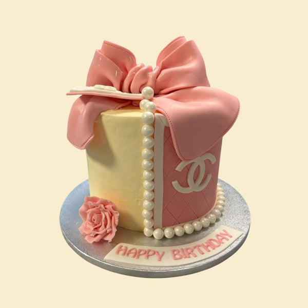 Rosa und cremefarbene Designer Handtaschen Motivtorte mit großer Schleife, Perlenkette und eleganter Steppoptik.