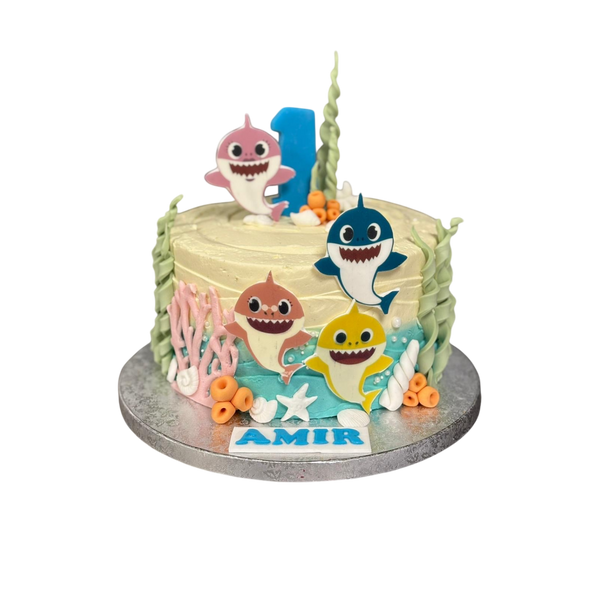 „Baby Shark Unterwasser-Geburtstagstorte mit essbaren Meeresdekorationen und Figuren. Individuell gestaltet mit dem Namen ‚Amir‘ und einer blauen Zahl 1 als Kerze. Perfekt für den ersten Geburtstag, mit wählbarer Wunschfüllung.“