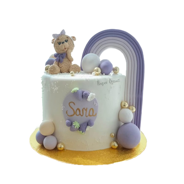 Weiße Torte mit  weiß-lila Kugel, Lila Regenbogen und Teddy mit Schleife