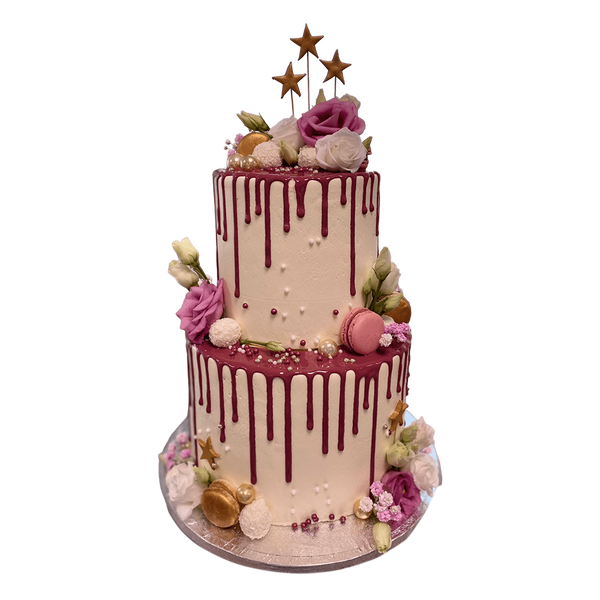 Zweistöckige Torte mit rosa Drip-Glasur, dekoriert mit Sternen, rosa Rosen, Macarons und weißen Blumen, präsentiert auf einer runden Basis.






