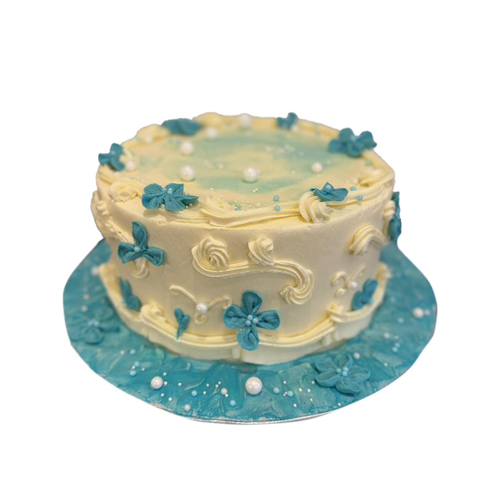 Weiße Torte mit blauen gespritzten Blumen, Perlen und weißer Spritzdeko