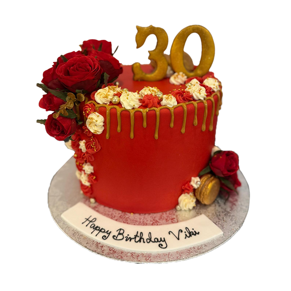 Roter Drip Cake mit  weißer Spritzdeko, goldenen Macarons und roten Rosen
