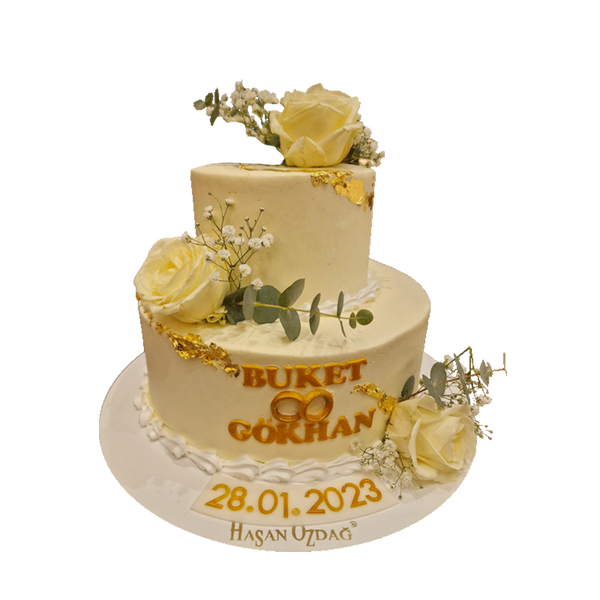 Zweistöckiger Hochzeitstorte, dekoriert mit weißen Rosen, Schleierkraut und Eukalyptusblättern. Goldene Akzente aus essbarem Blattgold verzieren die Torte.