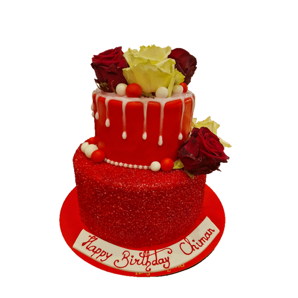 Zweistöckige Torte mit roten Fondant und Glitzer. Unter den Rosen ist weißer Drip.
